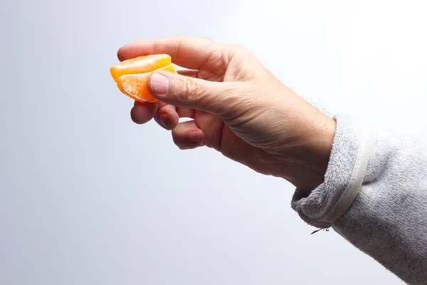 Fatia de tangerina na mão de uma pessoa adulta — Fotografia de Stock