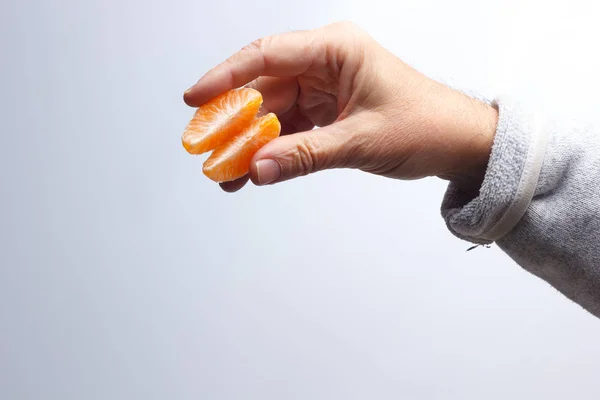 Tangerine slice in the hand of an adult person — Stockfoto