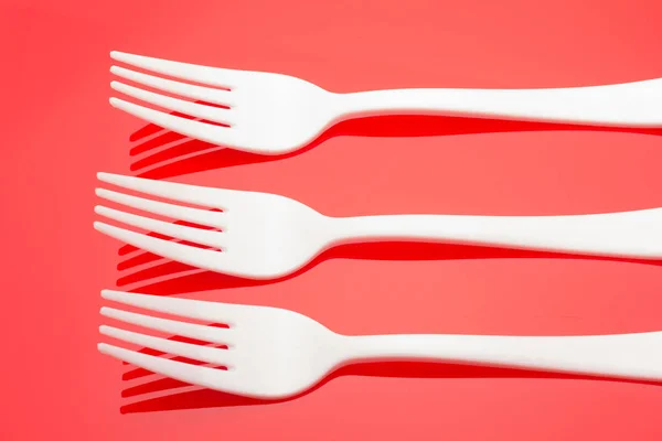 Plastic fork on colored background; fork for casual food, covered in white to prick and make casual food, ideal for family meals, parties, catering.