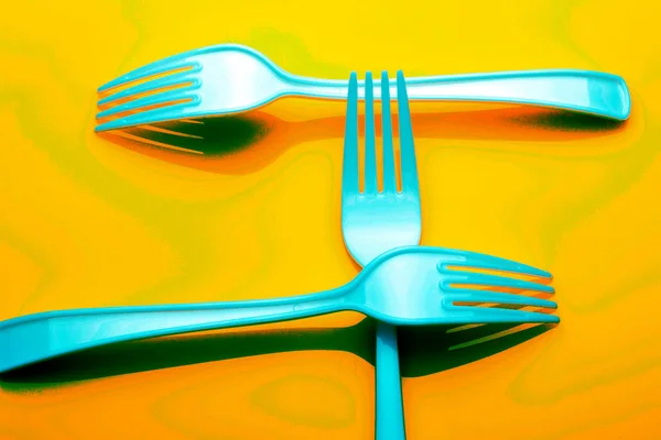 Plastic fork on colored background; fork for casual food, covered in white to prick and make casual food, ideal for family meals, parties, catering.