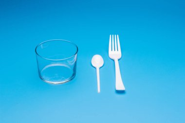 Cutlery for eating white and made of plastic and transparent glass cups; Cutlery and glasses teaspoons for coffee and for rationing small amounts of sugar, fork for pricking food, glasses for drinking