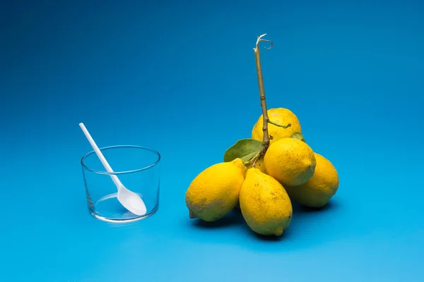 Healthy lemons with an acid flavor and full of vitamins, together with plastic cutlery; Citrus lemons on blue background.