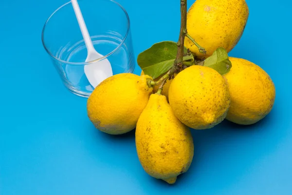 Healthy lemons with an acid flavor and full of vitamins, together with plastic cutlery; Citrus lemons on blue background.