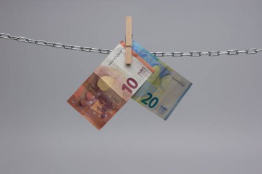 Avro banknotları, Avrupa ekonomisinin para birimi, 50, 20, 10 ve 5 avroluk bir zincirde asılı duruyor. Zincirlenmiş bir cımbızla asılı duran kağıt para..