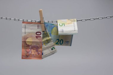Avro banknotları, Avrupa ekonomisinin para birimi, 50, 20, 10 ve 5 avroluk bir zincirde asılı duruyor. Zincirlenmiş bir cımbızla asılı duran kağıt para..