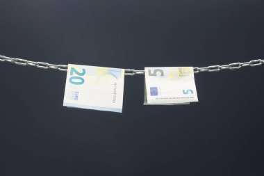 Money held in a chain or hung on a chain; paper money legal tender; Euros, currency of the European economic community, Common market.