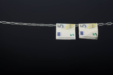 Money held in a chain or hung on a chain; paper money legal tender; Euros, currency of the European economic community, Common market.