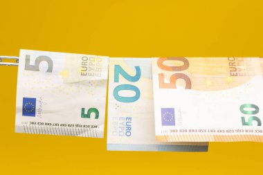 Money held in a chain or hung on a chain; paper money legal tender; Euros, currency of the European economic community, Common market.