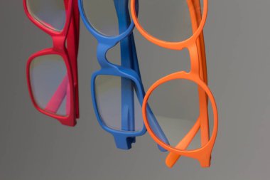 Gri zemin ve zincir üzerindeki renkli gözlükler; görme düzeltmesi için gözlük; okumak veya uzaktan görmek için lensler; gözlük insanların görüşünü iyileştirebilir.