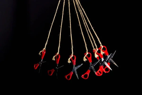 Scissors for manual work and school work, for cutting paper, cardboard, fabric, threads, twine; scissors hanging on string, multiple images of scissors on the same frame.