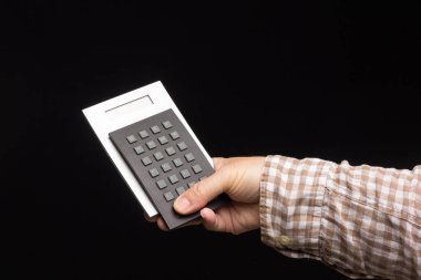 Matematiksel hesaplamalar bir hesap makinesiyle, siyah bir zemin üzerinde bir kişinin elinde yapılır..