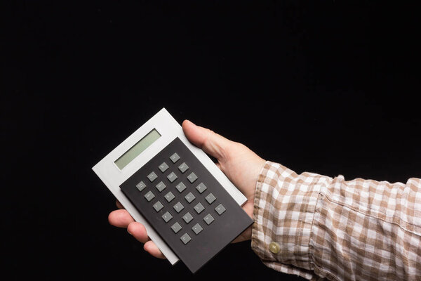 mathematical calculations performed with a calculator, in the hand of a person on a black background.