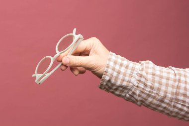 Bir yetişkinin elinde tasarım gözlüğü ve lensler, doğru görüş için düzeltilmiş gözlüklü gözlükler, modern tasarımı olan renkli gözlükler..