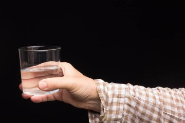 Bir insanın elinde şeffaf cam bardak. Bardak suyla ya da şeffaf sıvıyla dolu. İçme suyu