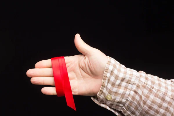 Ribbon to decorate gifts in the hand of an adult person on a plain background.