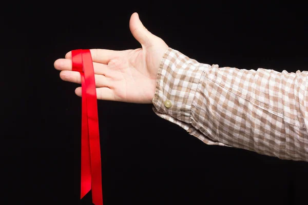 Ribbon to decorate gifts in the hand of an adult person on a plain background.