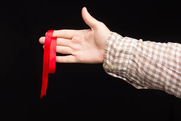 Ribbon to decorate gifts in the hand of an adult person on a plain background.