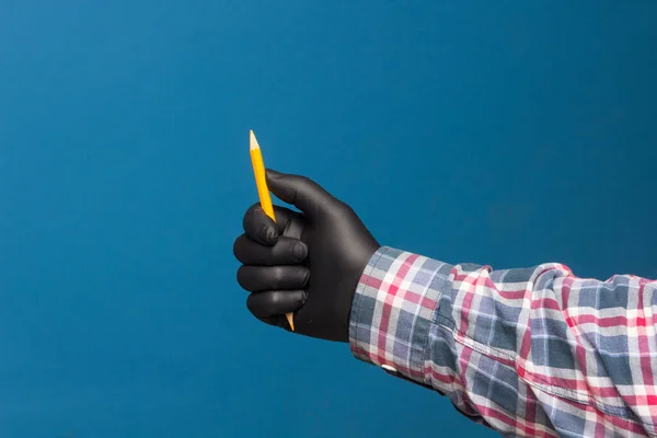 Color pencil with black hygienic protection glove on blue background. Pencil for drawing. pencil with sharp point