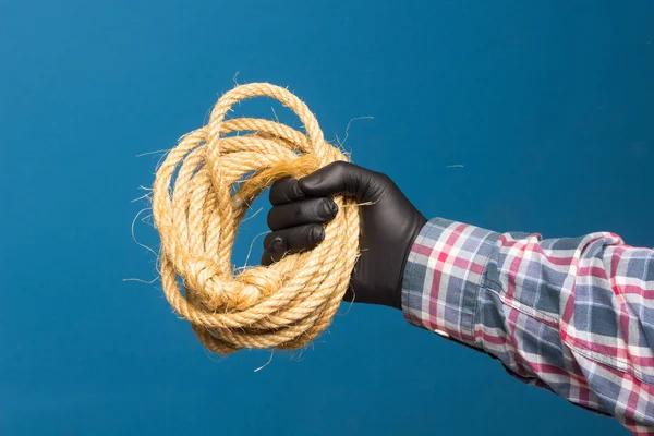 Yellow rope in the expert hand of an adult with protection. Thick rope to tie objects.