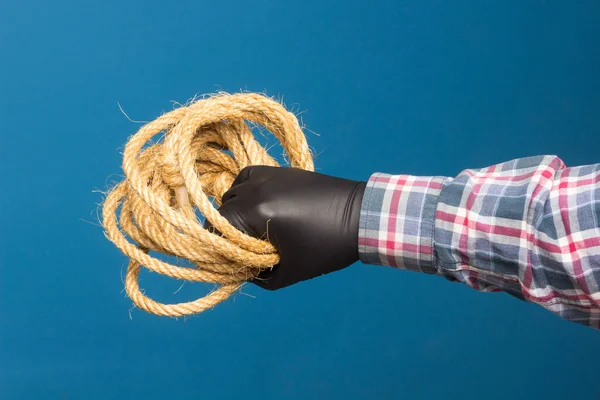 Yellow rope in the expert hand of an adult with protection. Thick rope to tie objects.