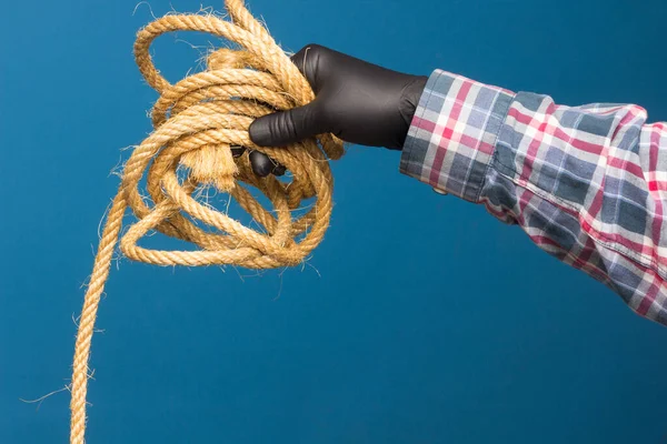 Yellow rope in the expert hand of an adult with protection. Thick rope to tie objects.