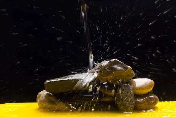 Crystal clear, drinkable and transparent water, falling on some stones and creating thousands of drops due to splashing and splashing water.