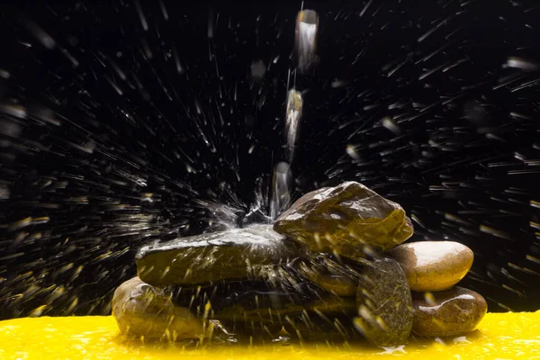 Crystal clear, drinkable and transparent water, falling on some stones and creating thousands of drops due to splashing and splashing water.