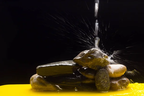 Crystal clear, drinkable and transparent water, falling on some stones and creating thousands of drops due to splashing and splashing water.