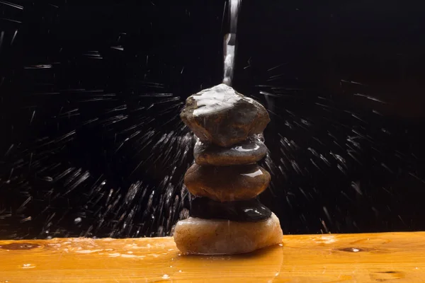 Crystal clear, drinkable and transparent water, falling on some stones and creating thousands of drops due to splashing and splashing water.