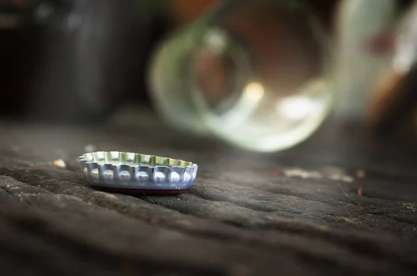 Şişe kapakları ahşap zemine ve düşen şişe ve bardakların bulanık arka planına yerleştiriliyor..