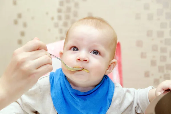 Mother feeds the little child at the table — Stock Photo, Image