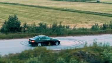 Siyah BMW arabası tarlaların yakınındaki asfalt yolda gidiyor. - Rusya. İHA atışı