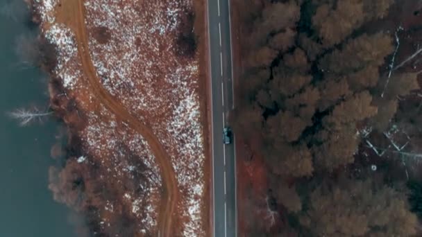 森林中的乡村道路上驾驶着黑色汽车的空中景象 电影无人驾驶飞机飞越河流附近的公路 — 图库视频影像