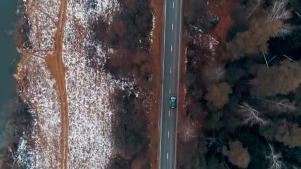 森林中的乡村道路上驾驶着黑色汽车的空中景象 电影无人驾驶飞机飞越河流附近的公路 — 图库视频影像