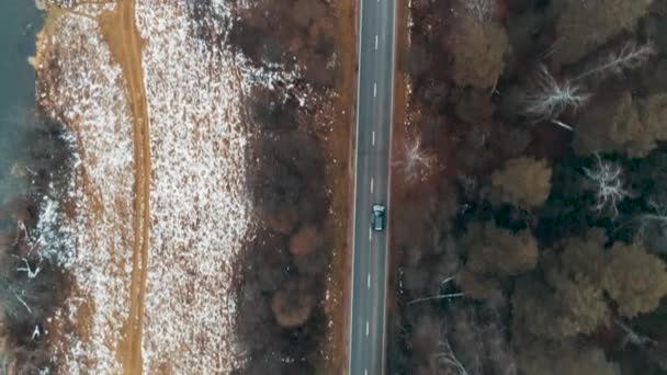Vue aérienne de la voiture noire conduisant sur la route de campagne en forêt. Drone cinématique survolant la route près de la rivière 