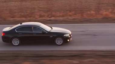 BMW 5 siyah araba yolda gidiyor. Ufuktaki güneş ışınları. Saint Petersburg 