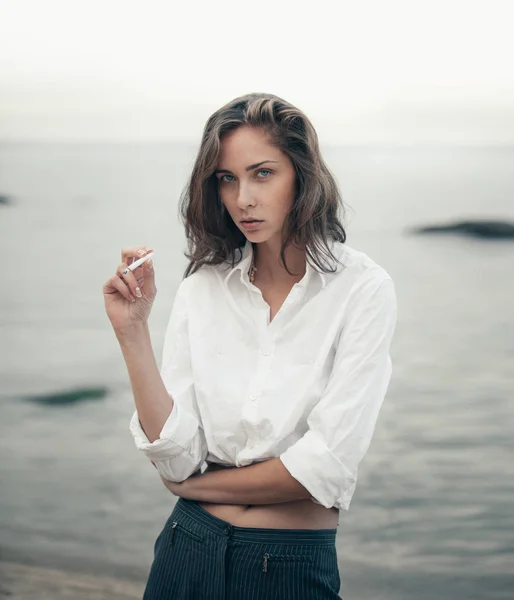 Söt kvinna röker en cigarett på stranden — Stockfoto