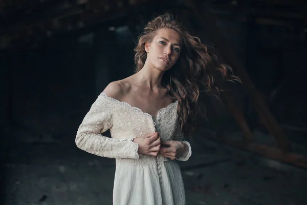 Hermosa chica en vestido vintage blanco con el pelo rizado posando en el ático. Mujer vestida de retro. Emoción sensual preocupada. Moda retro —  Fotos de Stock