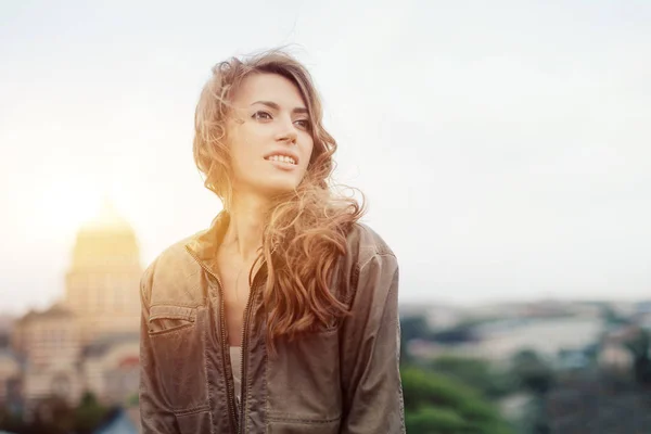 Giovane donna attraente con buon umore godendo bellissimo paesaggio della città mentre in piedi su un tetto di edificio, affascinante ragazza hipster sorridente rilassante dopo l'escursione durante il suo incredibile weekend di primavera — Foto Stock