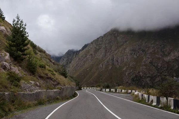 Cinematic road landscape. Asphalt Road throuth the mountains. With cloudy sky