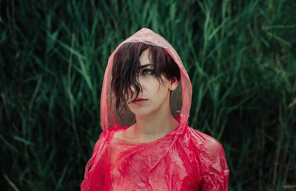 El retrato de niña en impermeable rojo bajo la lluvia . — Foto de Stock