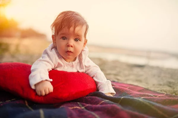 Baby ligt op plaid en kussen in park te lezen — Stockfoto