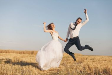 Güzel gelin ve damat buğday alanında. Mutluluk ve evlilik. Kadın beyaz elbise erkek beyaz gömlek ve kravat