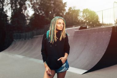 Güzel genç fitness kadın siyah hoodie ayakta skate Park.