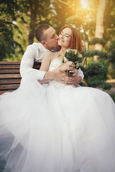 Brud i elegant brudekjole sidder på stenbænken - Stock-foto