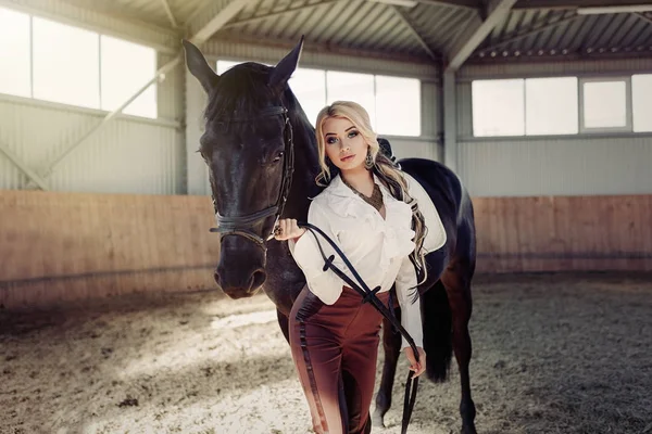 Linda menina loira elegante de pé perto de seu cavalo vestir competição uniforme — Fotografia de Stock