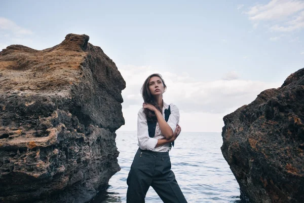 大きな石の上にコスト海近くスーツ ベストと白シャツに立ってビジネス女性 — ストック写真
