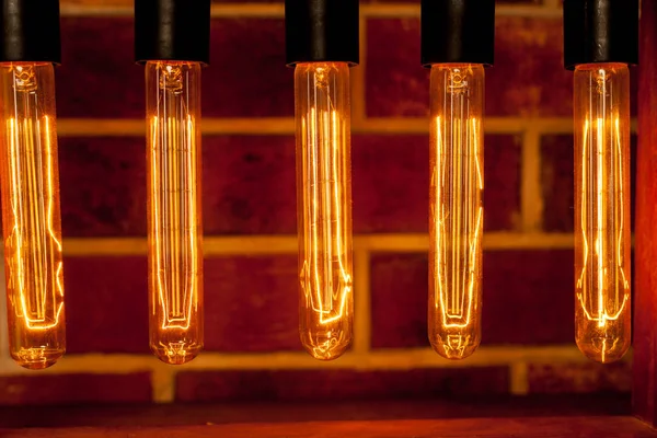 Lámpara de bombilla sobre fondo de ladrillo rojo oscuro con punto caliente cerca — Foto de Stock