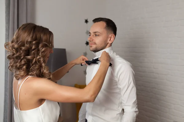 Наречена фіксує краватку на шиї нареченого, поки вони стоять — стокове фото