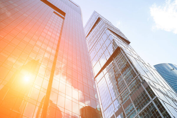 Detail blue glass modern office building background with cloud sky and sunlight